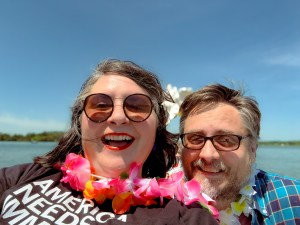 A picture of two people smiling with a lake in the background. 