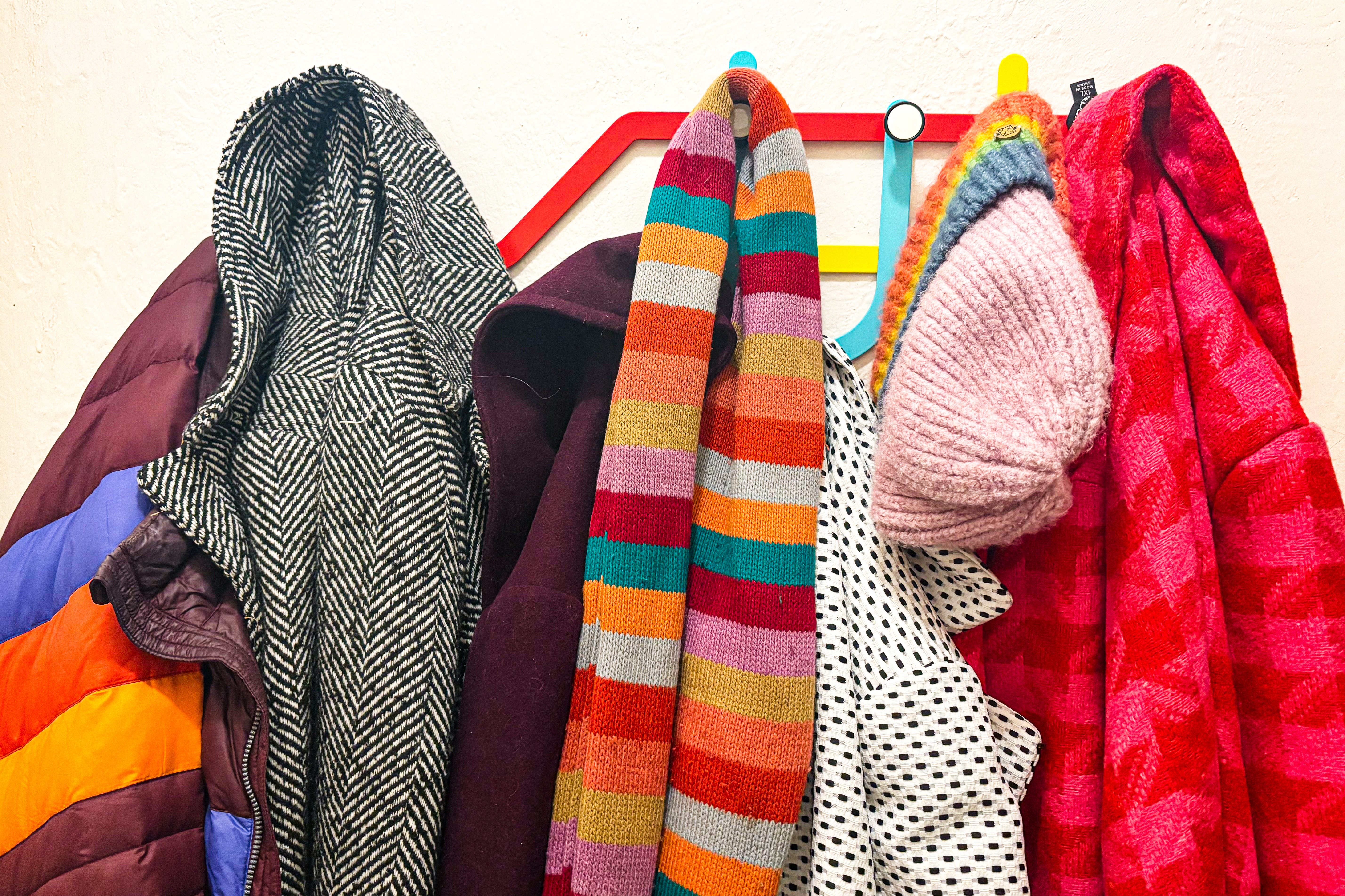 A rack with several colorful winter coats hanging from it. 