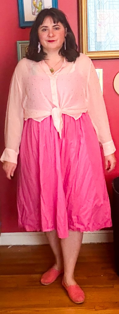 A pink dress layered with a sheer pale pink blouse. 