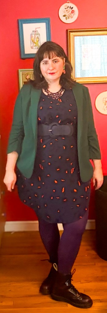 This bold outfit pairs a navy dress with a dark green blazer and dark purple tights. 